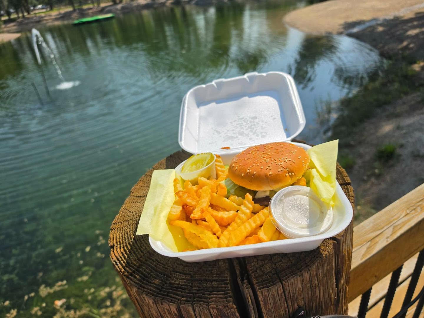Burger and crinkle-cut fries photographed beside the Mountain River Ranch pond in Ririe, Idaho