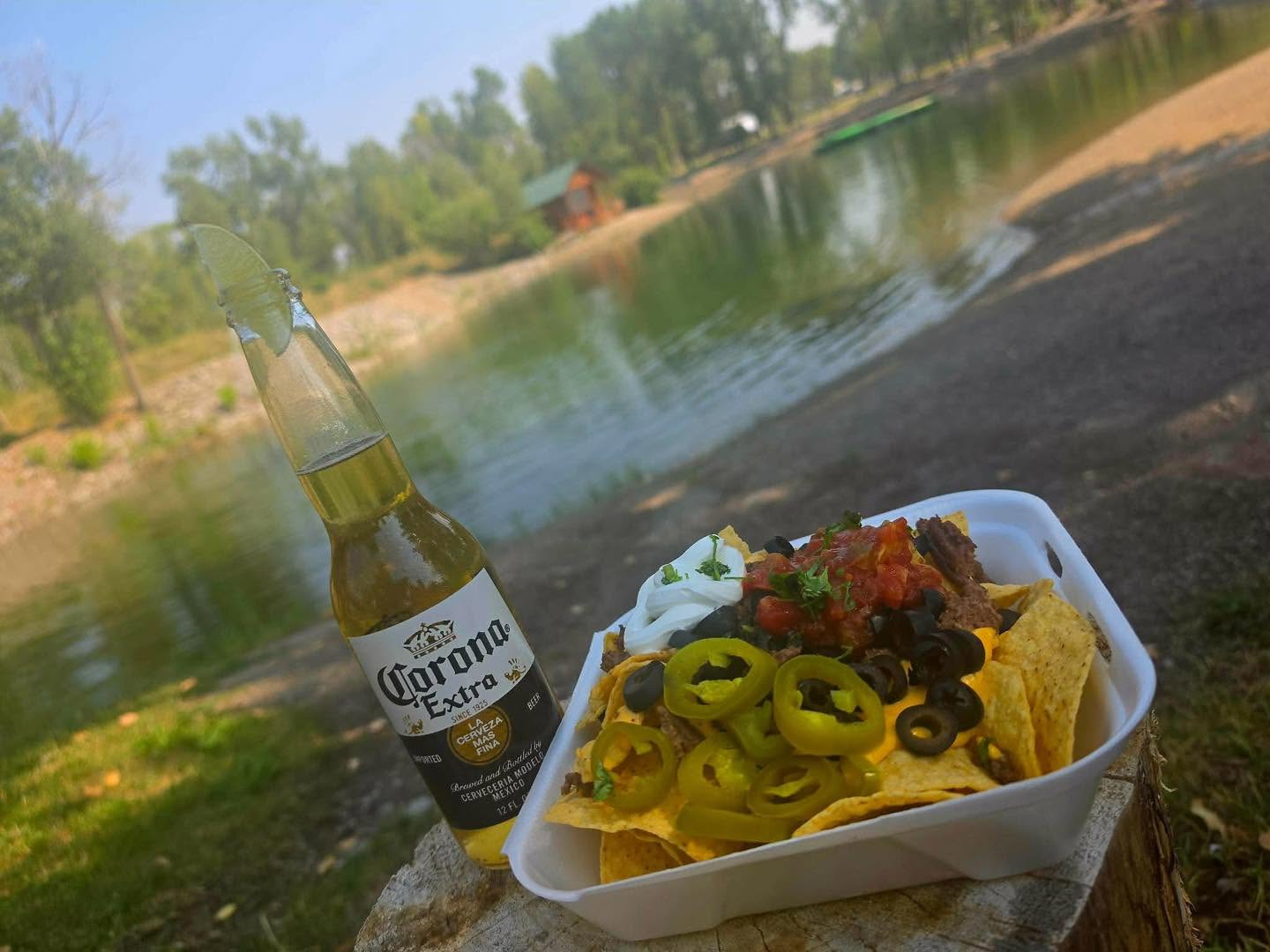 Loaded nachos and a bottled drink photographed by the pond at Mountain River Ranch